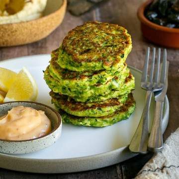 Stack of fritters in a plate with condiments on the side