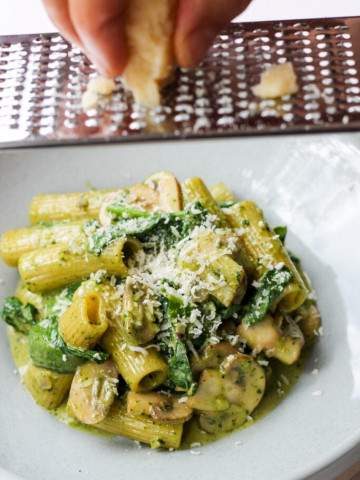 bowl of rigatoni with brown mushrooms and basil pesto sauce