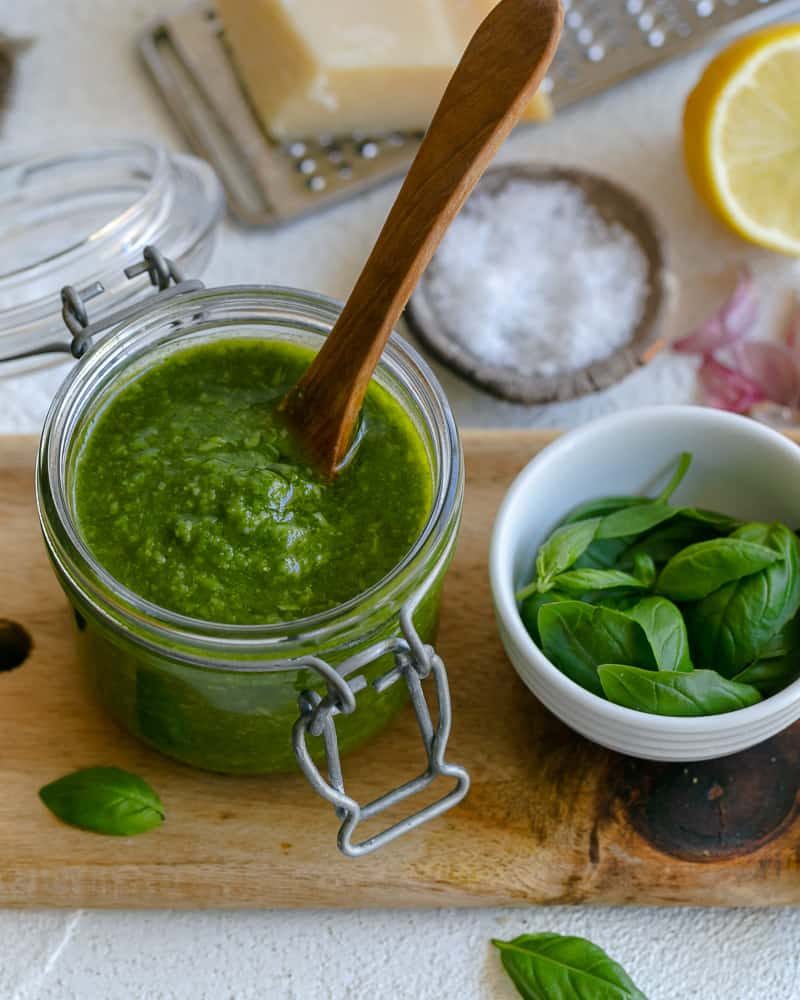 Basil Pesto in a jar with a wooden spoon in it