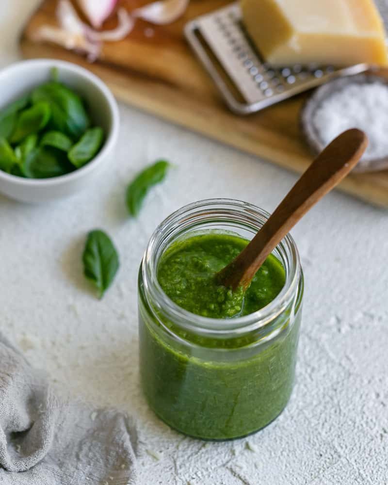 Basil Pesto in a glass jar with a wooden spoon
