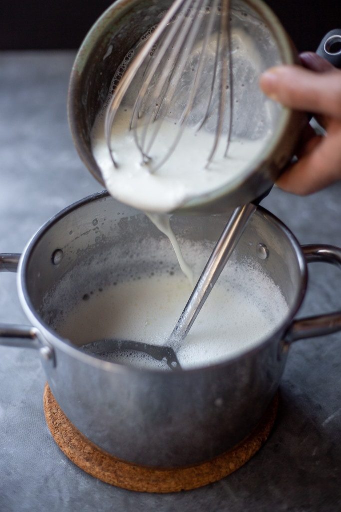 Adding yoghurt starter to a pot of warm milk