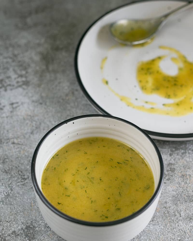 Nordic Style Easy To Make Mustard And Dill Sauce in a white bowl and a plate in the background with the sauce spoon