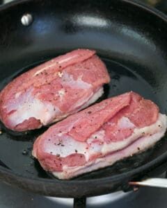 Two Duck breasts skin down in hot pan