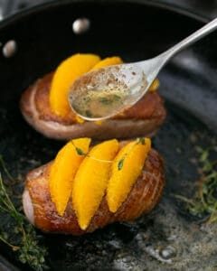 Orange segments on pan fried duck breasts while butter basting