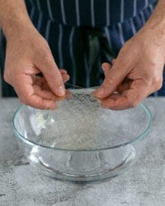 Gelatin sheets being submerged in a bowl of water