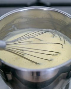 Creme fraiche, coconut milk and sugar in a pot with a whisk in it