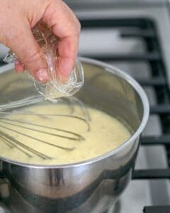 Drained gelatin being added to warm panna cotta mix