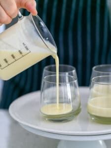 Panna cotta mix being poured into dessert glasses to set