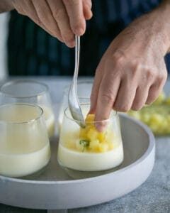 Adding pineapple on top of set panna cotta in a desert glass