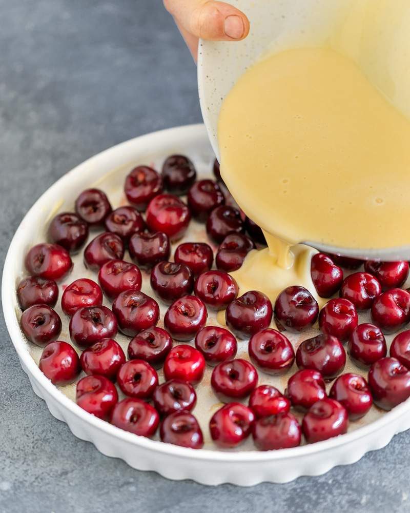 Clafoutis batter poured over the cherries