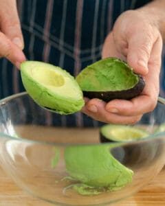 Scooping the avocado flesh with a spoon from the avocado skin