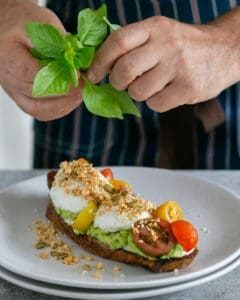 Adding fresh basil leaves on top of dukkah