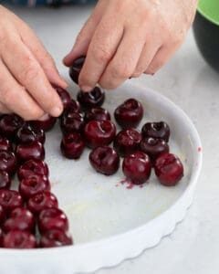 Arranging pitted cherries on a greased baking dish
