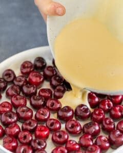 Batter poured of arranged cherries in baking dish