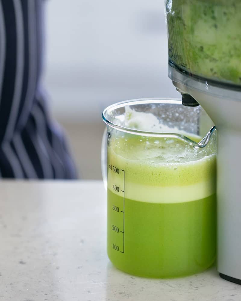 Apple juice in a measuring jug under a juicer