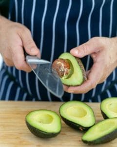 Avocado stone being removed with a knife
