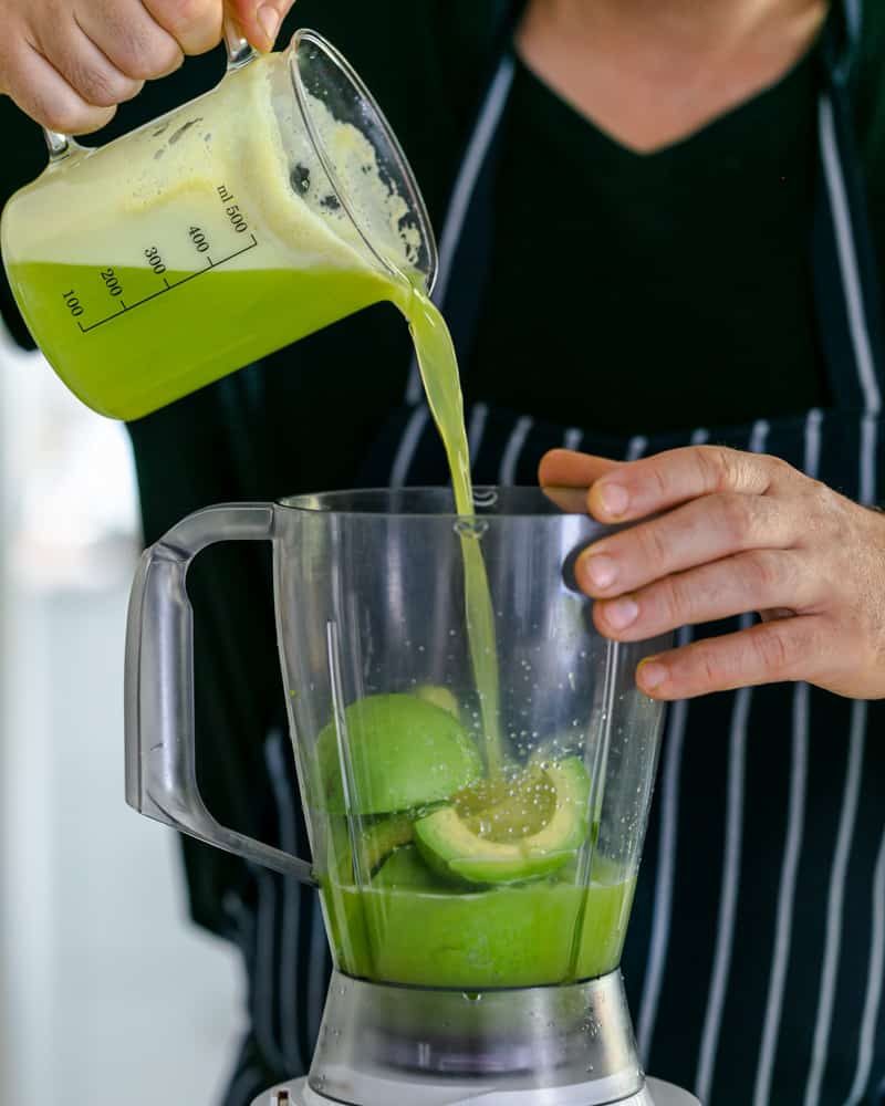 Apple juice mixed with lime juice being poured over avocados in the mixer