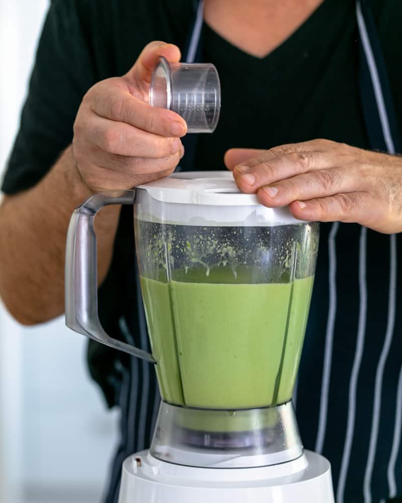 Apple juice mixed with lime juice being poured over avocados in the mixer