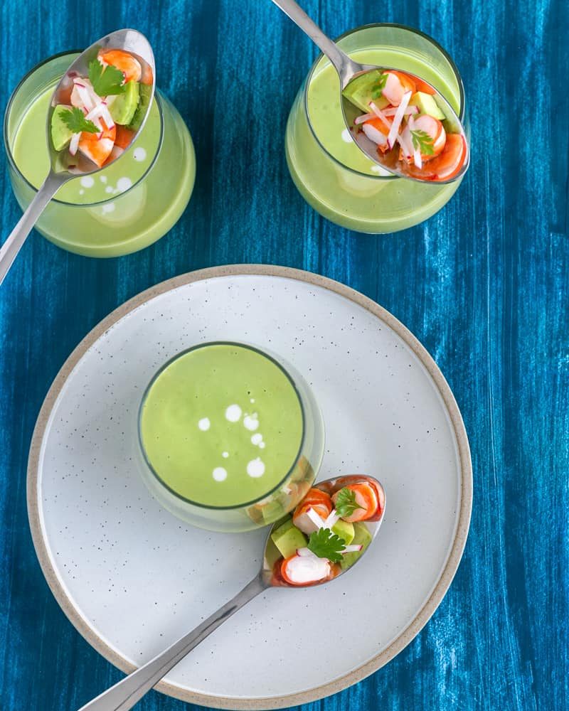 Canape style avocado and green apple soup in a dessert glass with prawn salad on a spoon