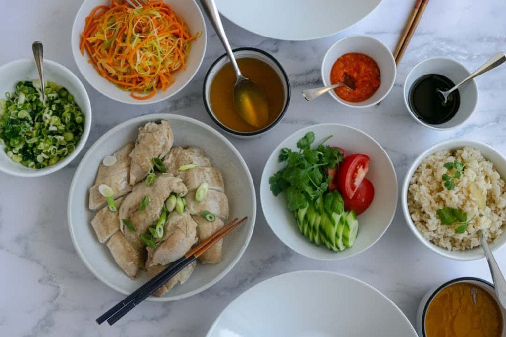 Overhead shot of the whole chicken, ginger rice, Chilli sauce and all other condiments