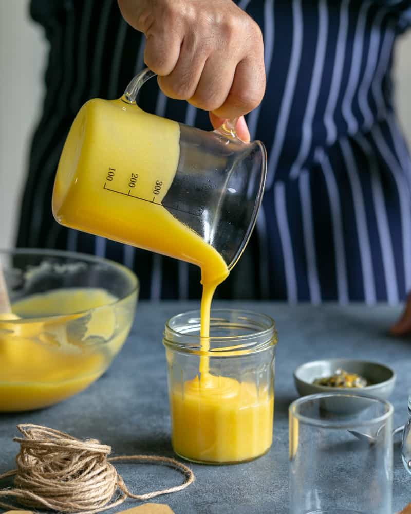 Pouring Passion fruit and lemon Curd in glass Jars
