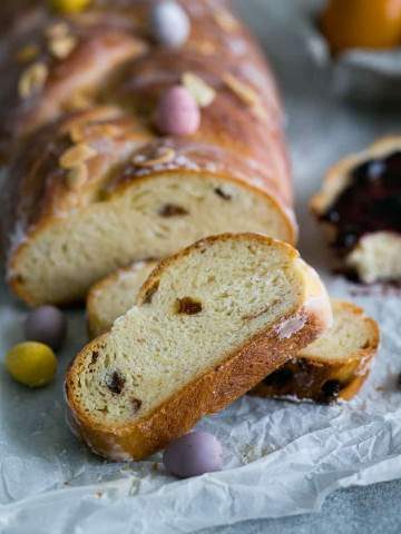 Sliced Easter Zopf with Raisins and Lemon Glaze decorated with small colourful chocolate Easter eggs