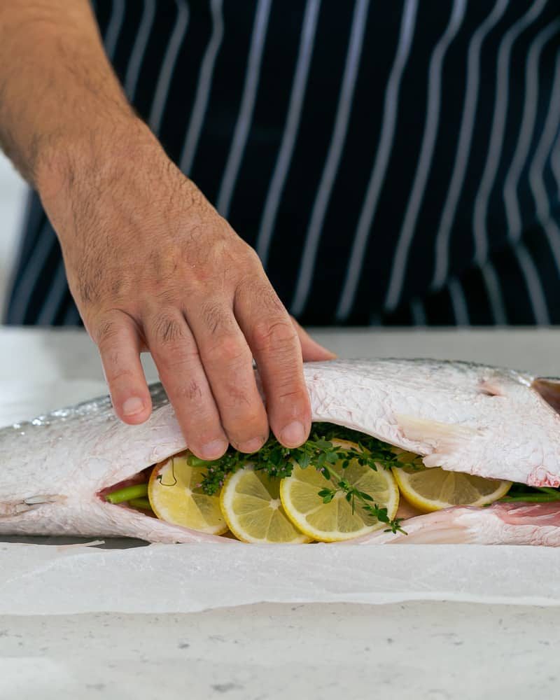 Whole Barramundi stuffed with Herbs and Lemon for salt-baking and served with salsa verde