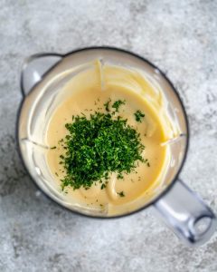 Chopped herbs added to the aioli in the blender