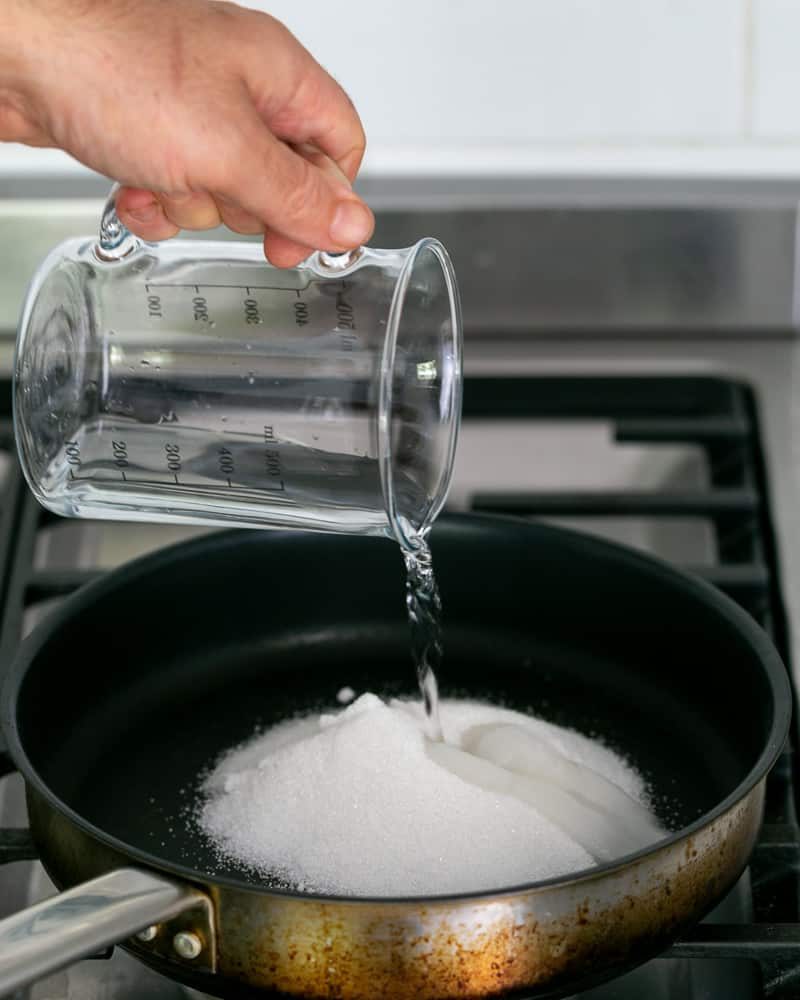 Adding water to sugar in the pan to make caramel