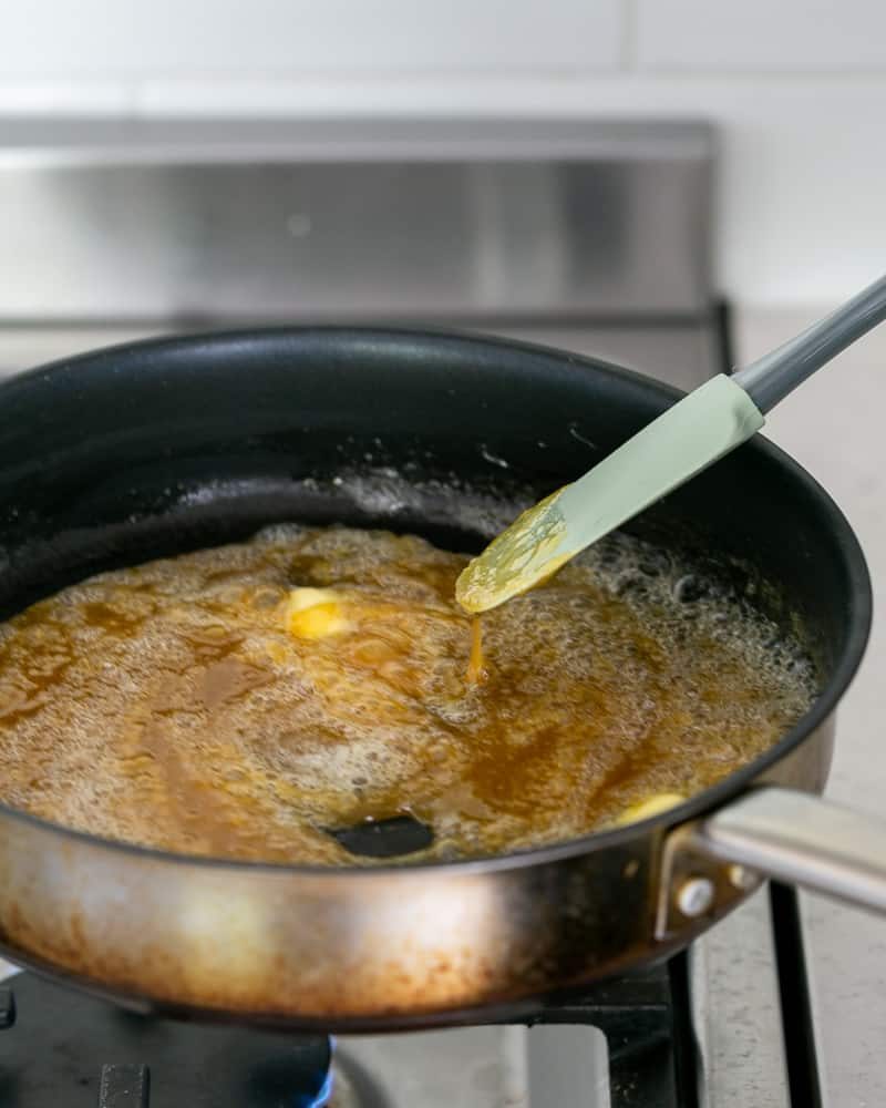 More unsalted butter cubes added to the caramel in the pan