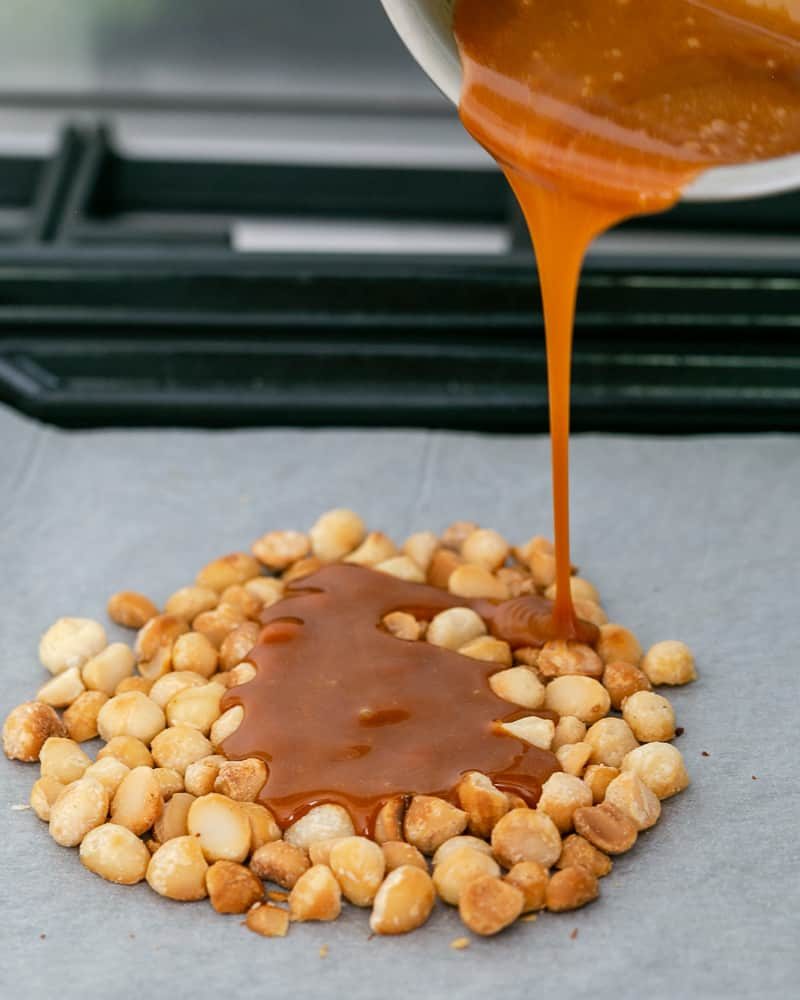 Pouring the hot caramel on the oven roasted macadamia nuts