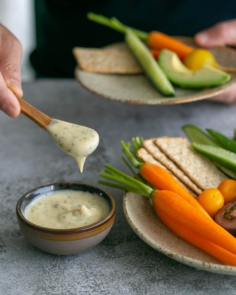 Taking a spoonful of Aioli to eat with crudities and crackers in a plate