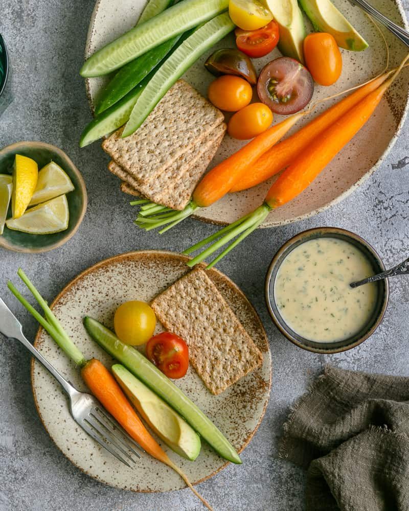 Overhead view of variety of crudities in a plate with som elemon wedges and garlic aioli in a small bowl on the side