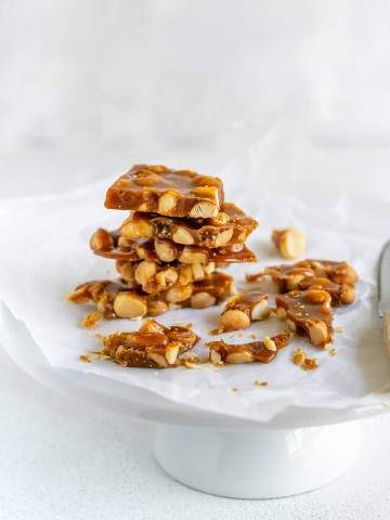 Stack of crispy macadamia nut brittle on a white cake stand