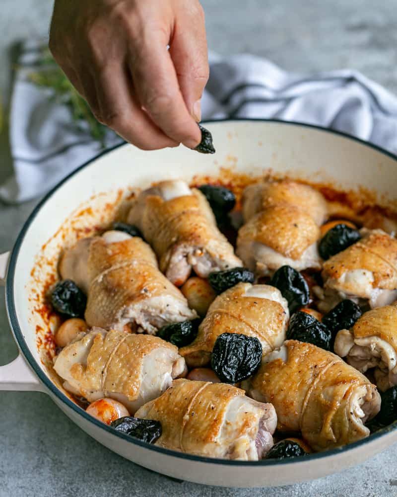 Adding prunes to the chicken thighs in the pan