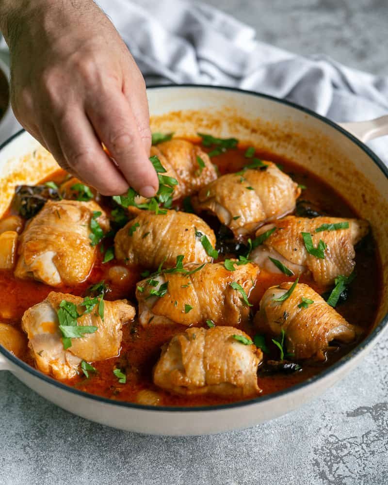 Fresh chopped parsley added over the chicken braised with pruned and shallots in the pan