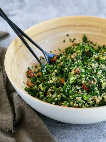 close up picture of prepared Tabbouleh Salad in a large wooden bowl with salad serving spoons