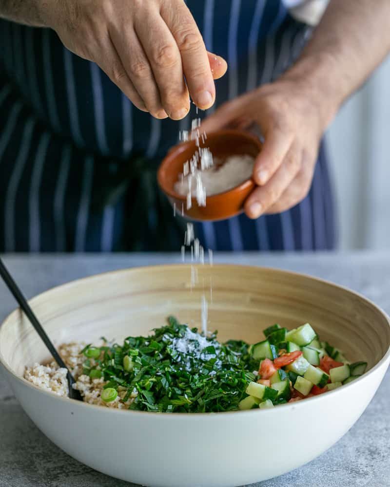 Seasoning the salad with fresh pepper and sea salt