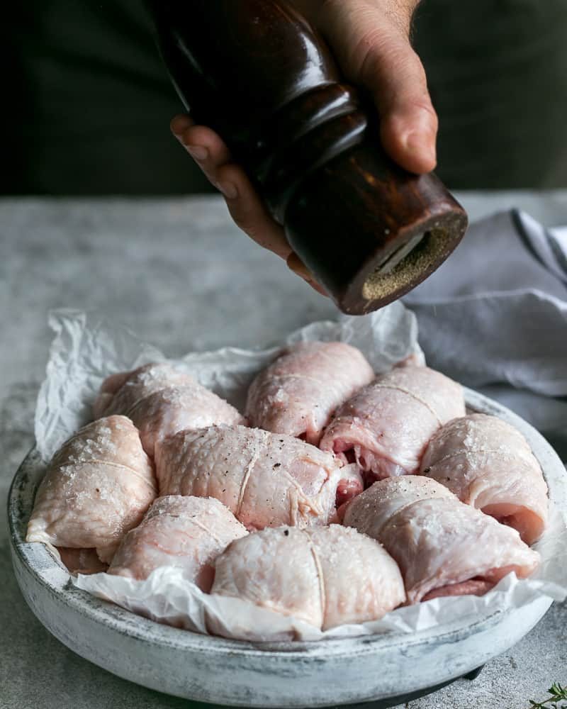 Seasoning tied chicken thighs with salt and pepper