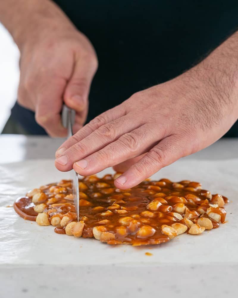 Cutting the macadamia nut brittle with a knife for more even pieces
