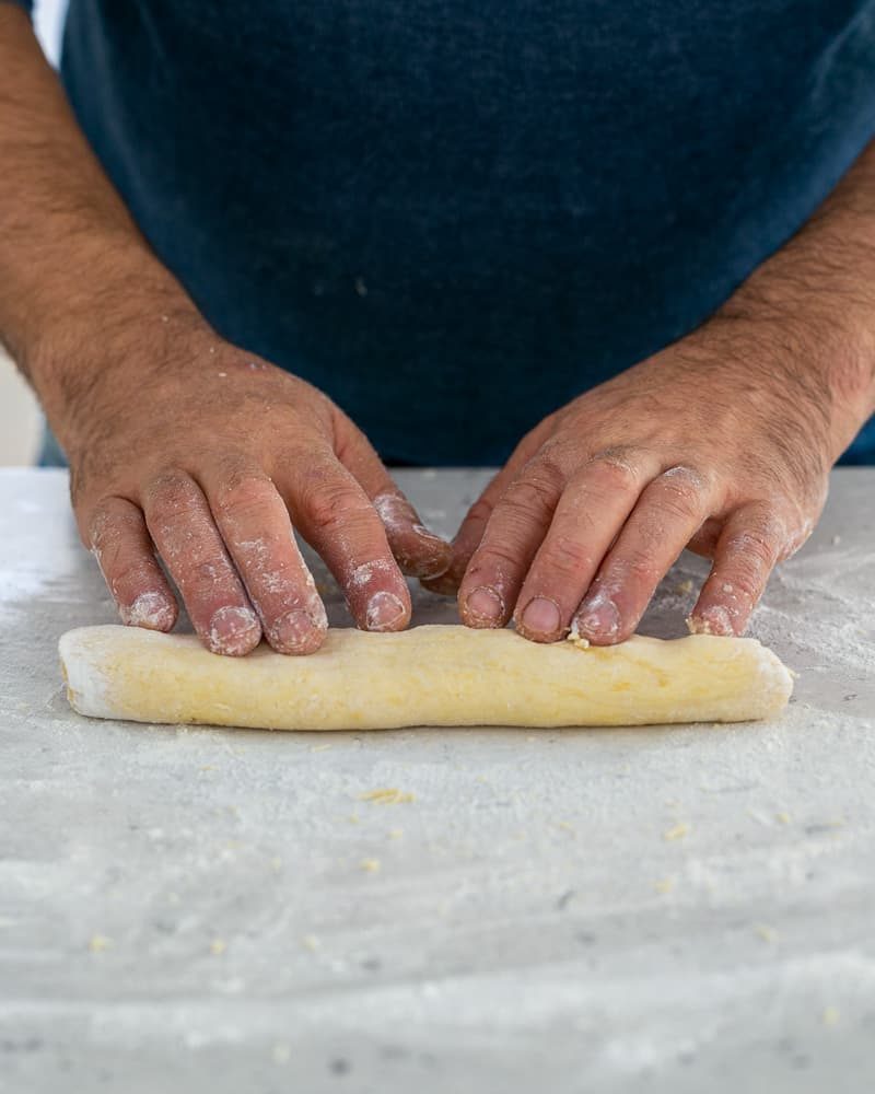 Rolling the dough to make ricotta gnocchi's with tomato and olives