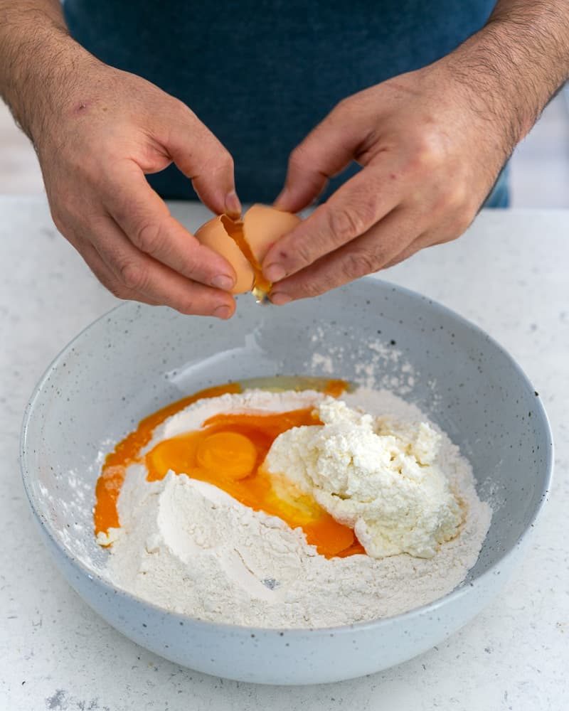 Adding eggs to the Flour and ricotta in a bowl 