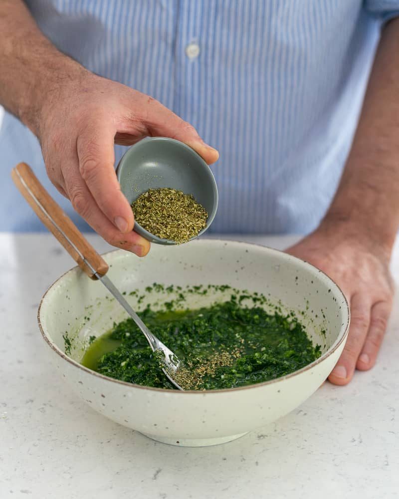 Adding oregano to prepared chimichurri