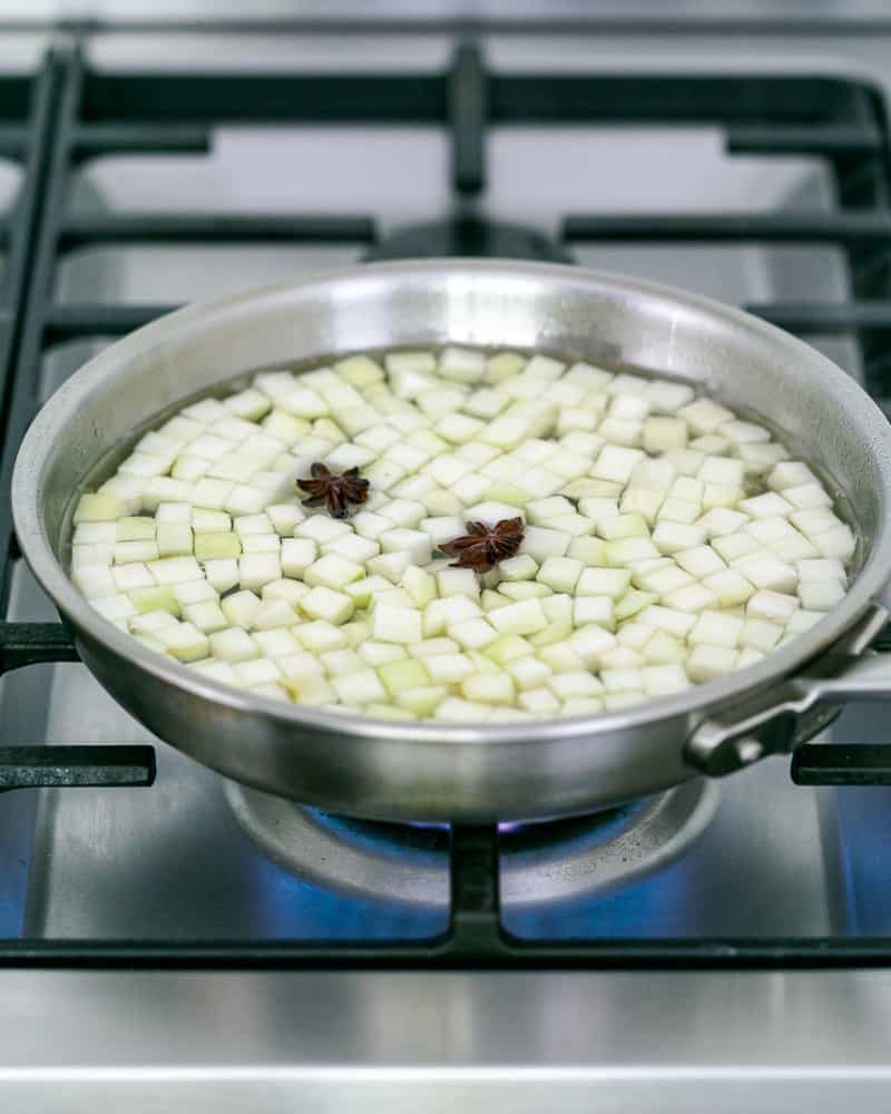 Poaching diced pears in sugar water flavoured with star anise