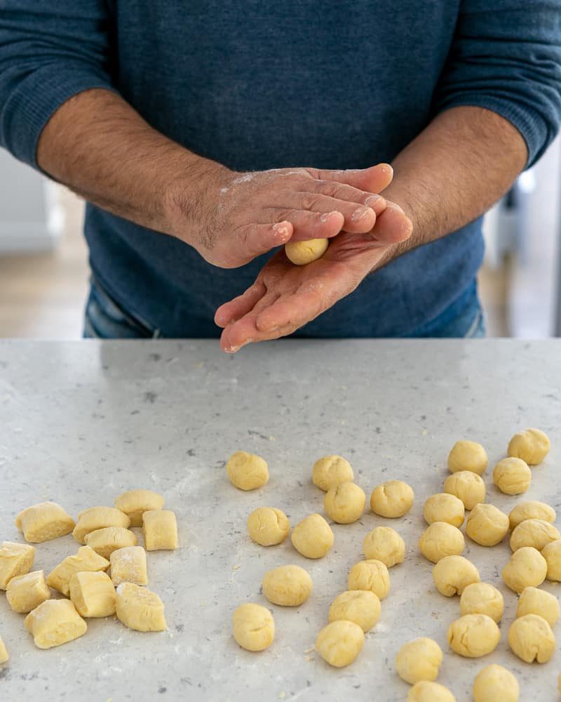 Rolling the dough into balls to make ricotta gnocchi's with tomato and olives