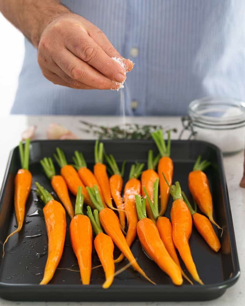 Season baby carrots with salt and pepper before roasting in the oven