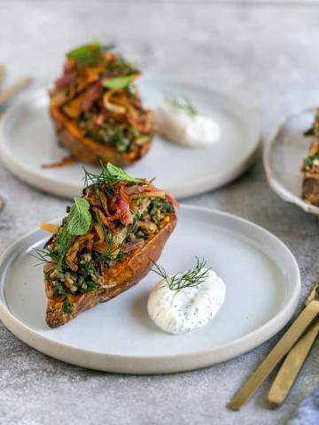 Baked Sweet Potato with Lentils and Swiss Chard served in a plate with labneh on the side