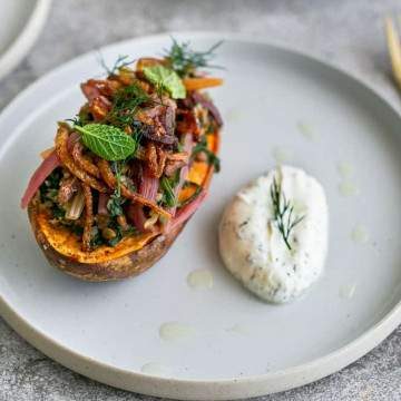 Baked Sweet Potato with Lentils and Swiss Chard served in a plate with Labneh on the side