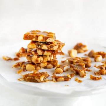 Stack of crispy macadamia nut brittle on a white cake stand