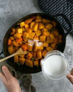 Ginge, garlic, curry powder added to roasted vegetables in stew pot